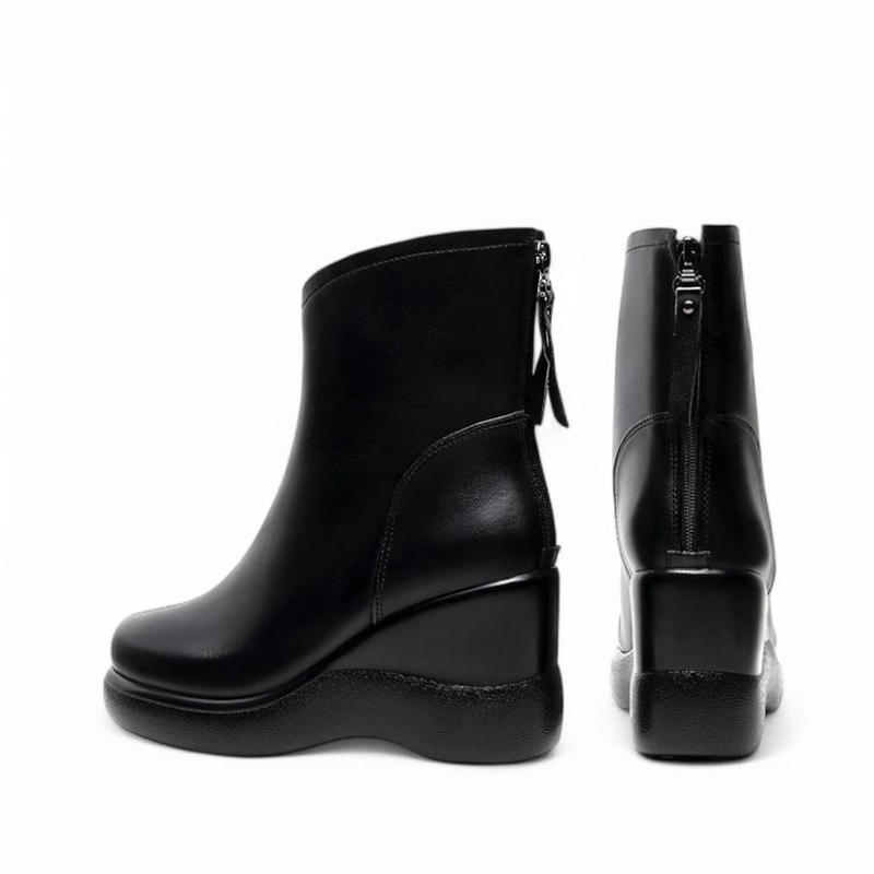 Back view of a pair of black wedge ankle boots placed side by side, with one boot standing upright and the other slightly tilted, showing the heel shape and zipper lines on a white background.