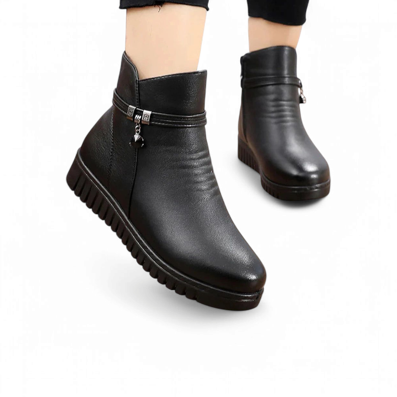 Two black flat ankle boots with front zippers, one foot stepping forward.