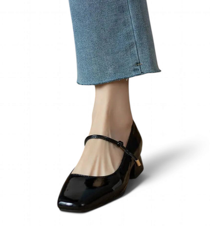 Glossy black Mary-Jane with square toe and mid block heel, shown with cropped denim.