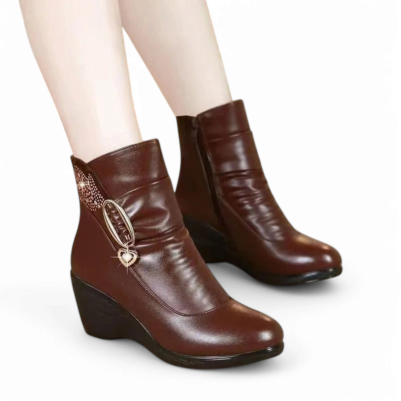 Brown leather wedge ankle boots with small heart charm and side zipper, worn on feet.