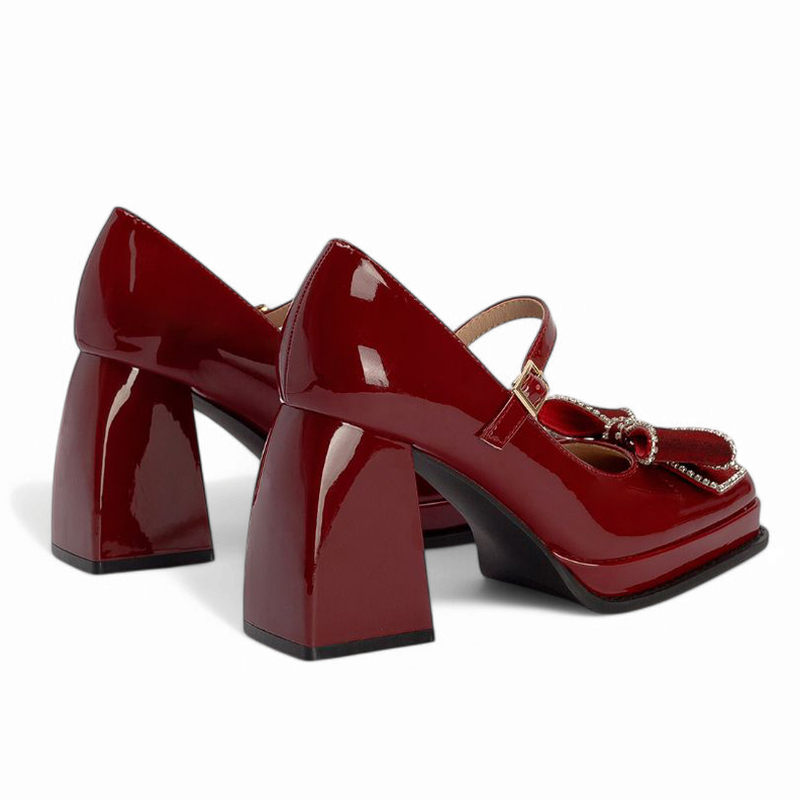 Rear view highlighting flared chunky heels and black outsole, reflecting the burgundy patent shine.