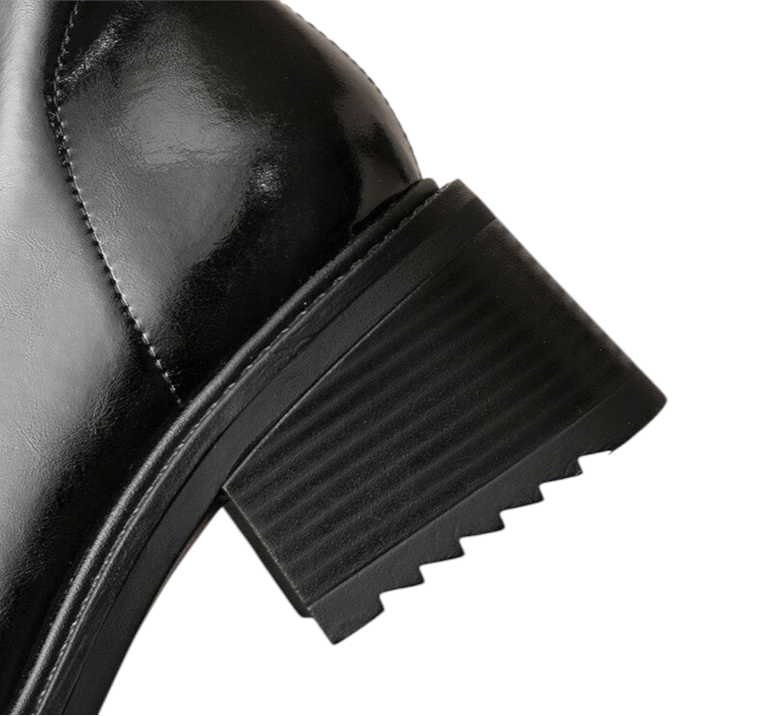 Close-up view of glossy black leather boots heel showing texture and craftsmanship.
