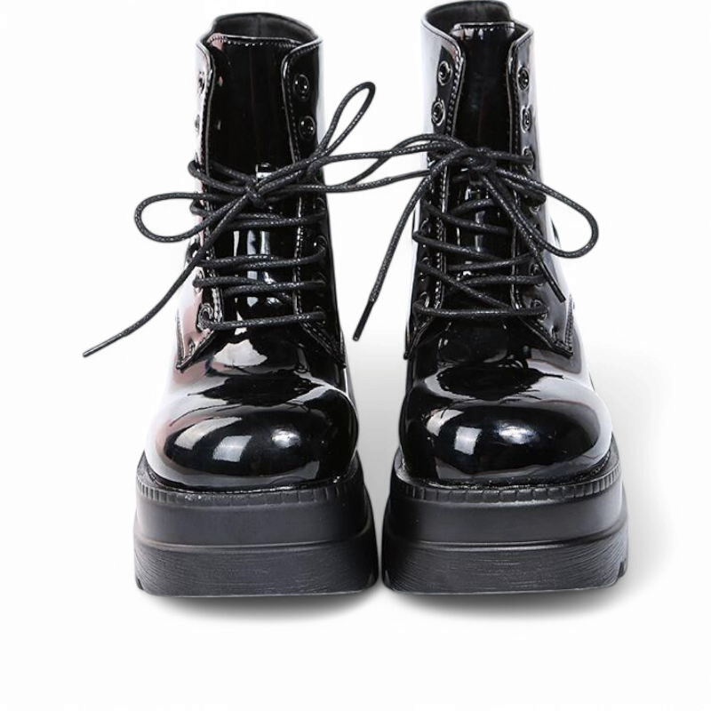 Front view of glossy black platform boots, laces untied.