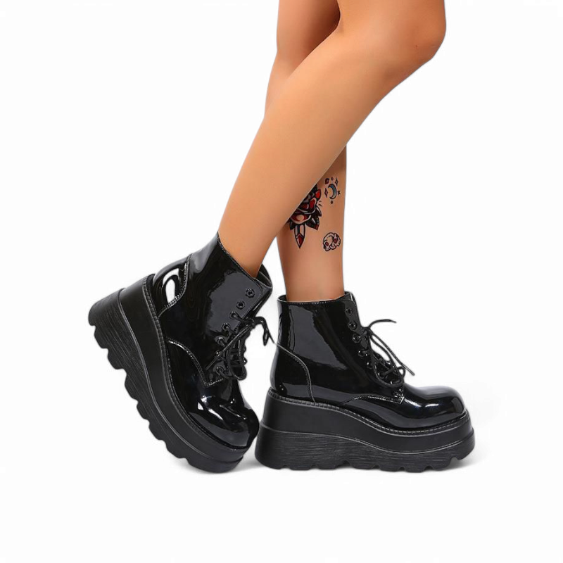 Glossy black ankle boots with high platform wedge, shown on crossed legs.