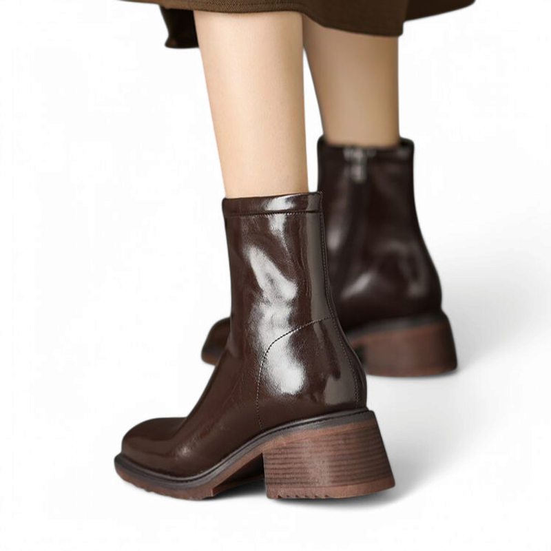 Woman wearing glossy brown leather boots with square toe and block heel styled in a chic outfit