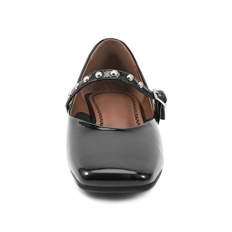Straight front shot highlighting glossy finish, square toe, and studded instep strap.