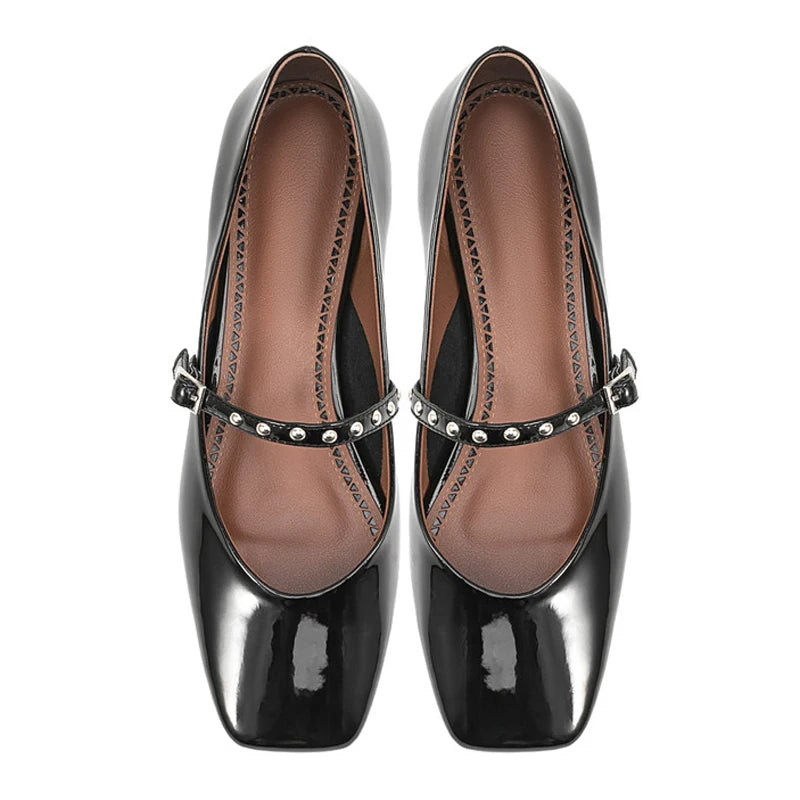 Overhead shot of black patent flat Mary Jane pair showing soft square toe and studded strap.