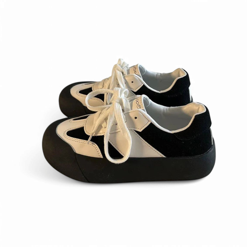 Pair of black-and-white sneakers with round toe and dark chunky sole.