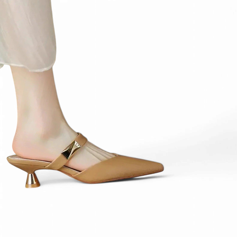 beige mule with gold strap and trumpet heel on a bare foot.