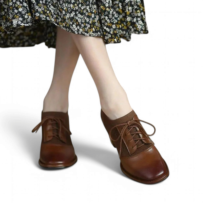 Pair of brown lace-up ankle shoes with square toes; front view styled with a floral skirt.