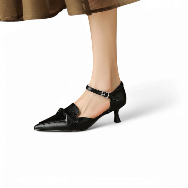 Black cow-leather pump with pointed toe, adjustable ankle strap and straight kitten heel, shown on foot.