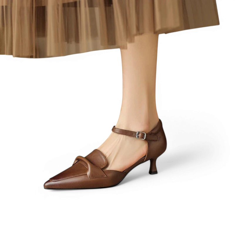 Chocolate smooth-leather pump with pointed toe, slim ankle strap and 4 cm kitten heel, worn with tulle skirt.