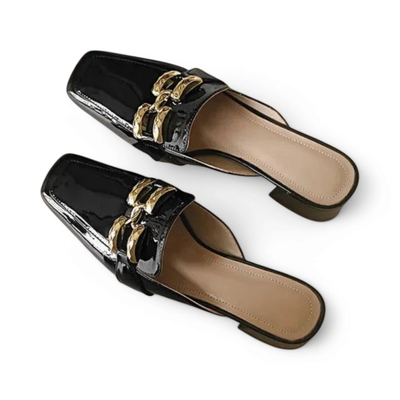 Pair of glossy black square‑toe mules with twin gold chains, angled top view on white background
