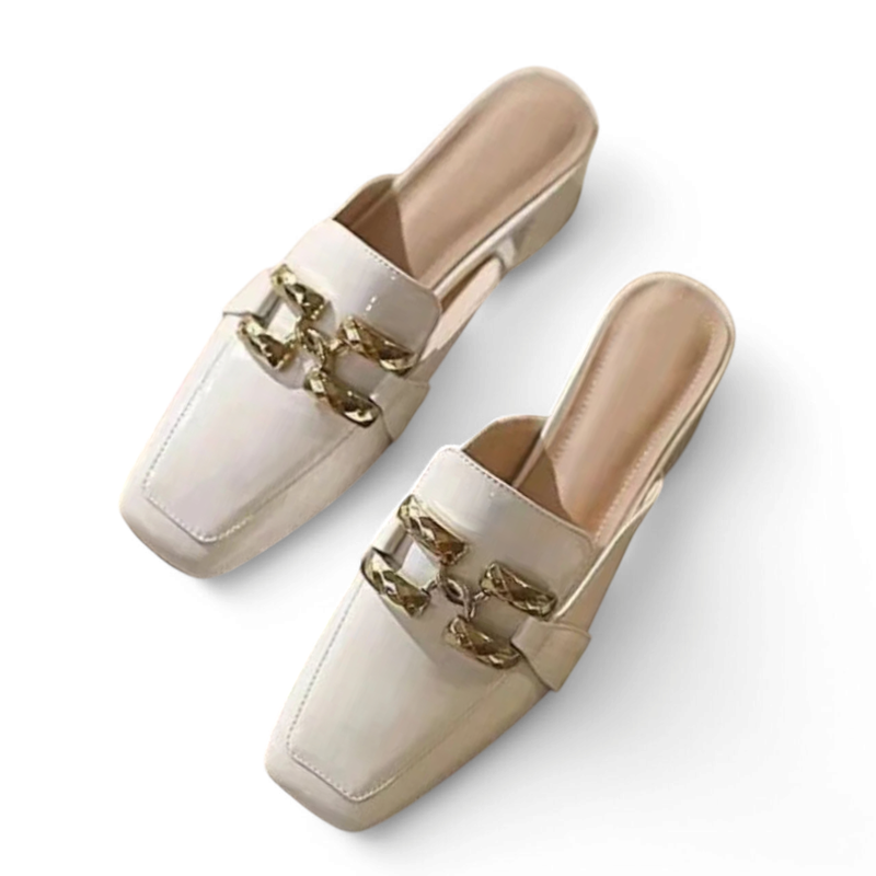 Glossy ivory mule pair laid flat, highlighting gold chain