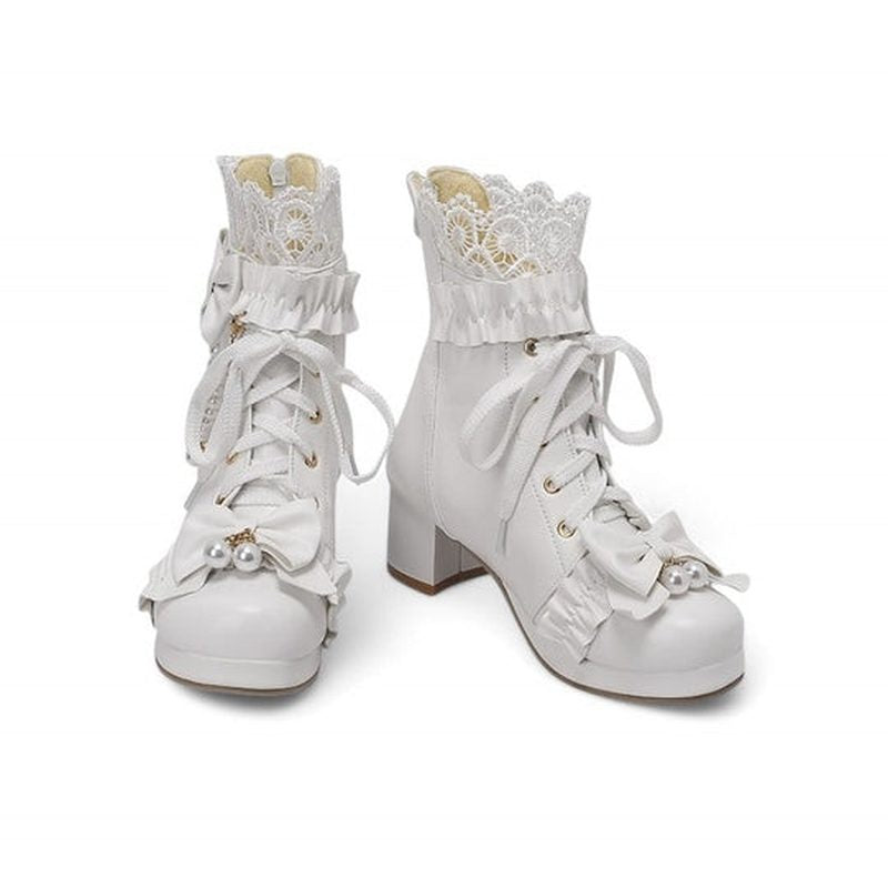Two Merendy Sydaty white Victorian boots on a white background. One boot is standing straight, the other is leaning slightly to the left. The image shows the lace cuffs, bows, pearls, and chunky heels from a soft side angle.