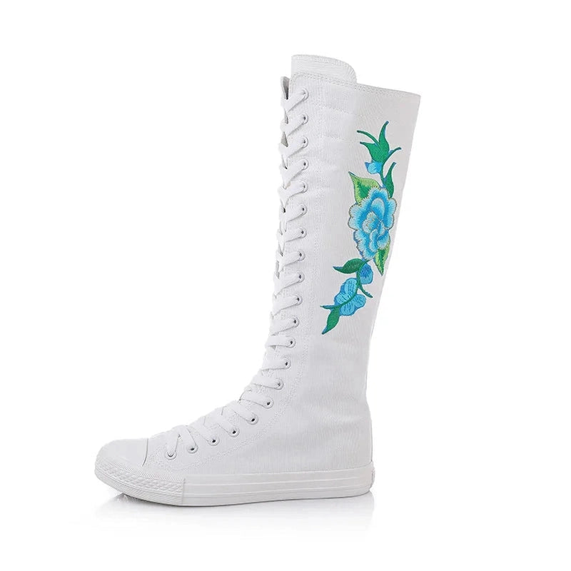 White knee-high canvas boot with vertical blue floral embroidery.
