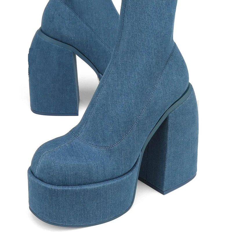 Macro shot of square toe resting on tall denim-wrapped platform.