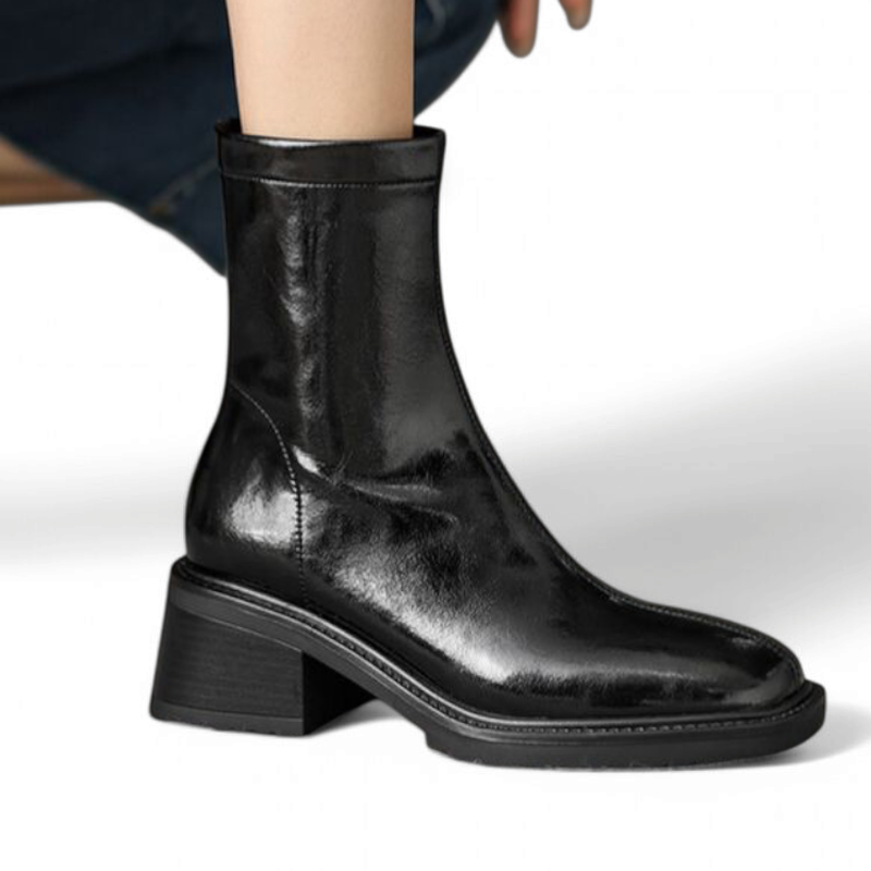 Side profile of a sleek black mid-calf boot with square toe and low stacked heel in worn