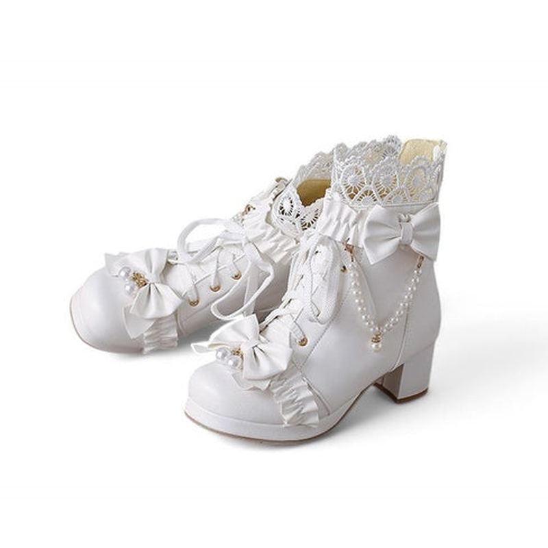 A slightly angled side view of the Merendy Sydaty white Victorian boots. One boot is gently resting over the other, showcasing the square toe, lace-up front, pearl bows, and floral lace trim in a soft, elegant arrangement.