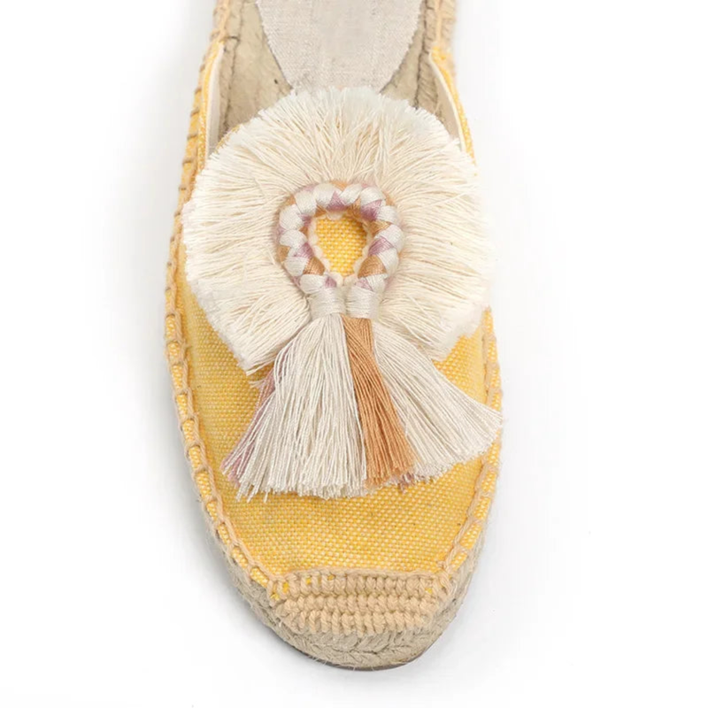 Close-up of yellow mule showing braided tassel detail