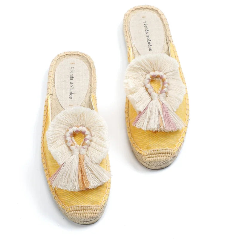 Yellow espadrille mules with cream fan fringe, angled view