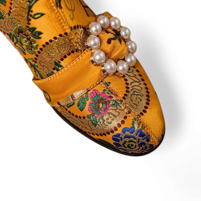 Top view of the yellow boot toe with satin strap and circular pearl buckle.