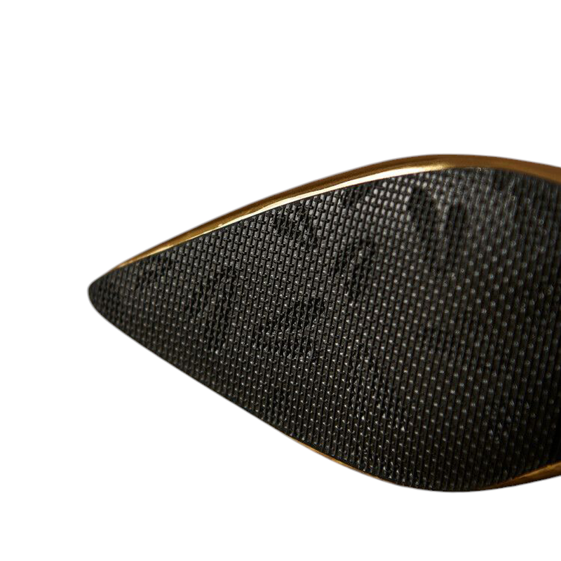 Macro of textured black rubber outsole with gold edge.