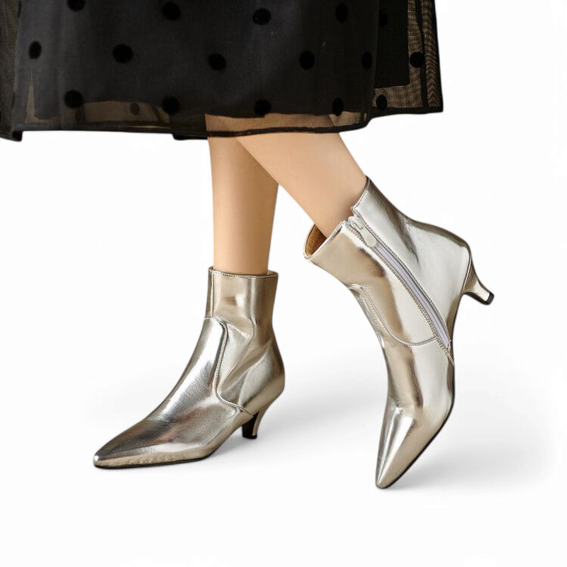 Woman wearing silver ankle boot, side zipper half-open.