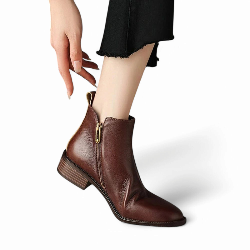 Brown boot on foot with hand pulling the side zipper