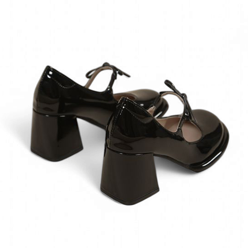Rear angled view of glossy black Mary-Jane pair highlighting geometric block heels.