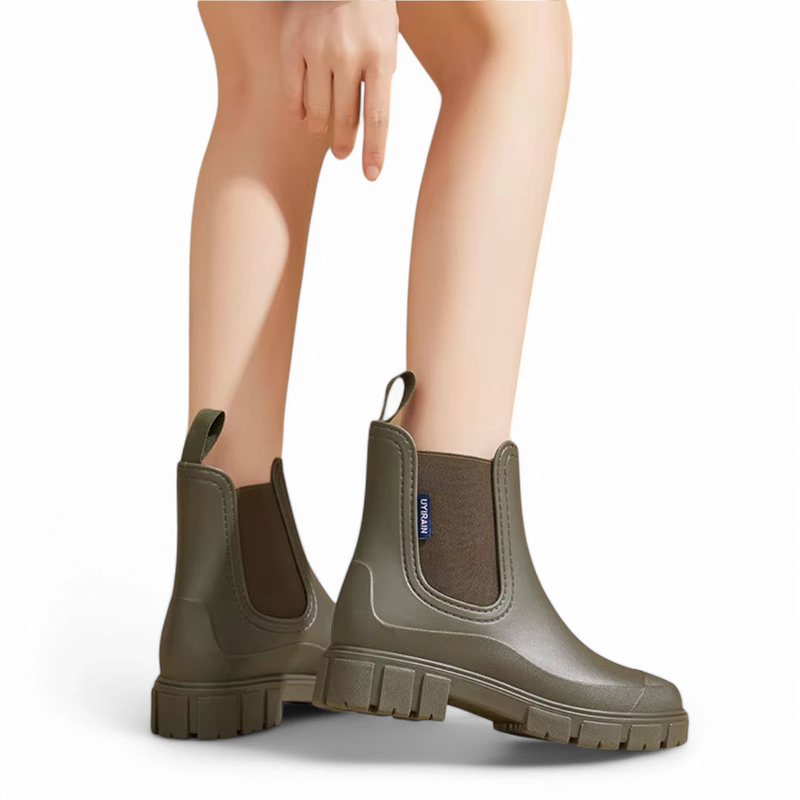 Green Chelsea boots positioned side by side, thick sole and elastic side panels visible.

