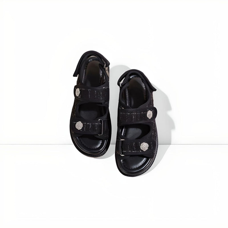 Flat-lay of black tweed-fabric platform sandals with two Velcro straps and round silver buttons.