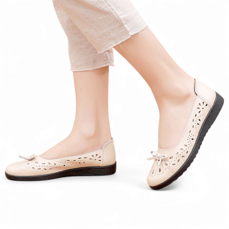 Beige round-toe ballet flat with decorative cut-outs and small bow, shown on-foot side view.