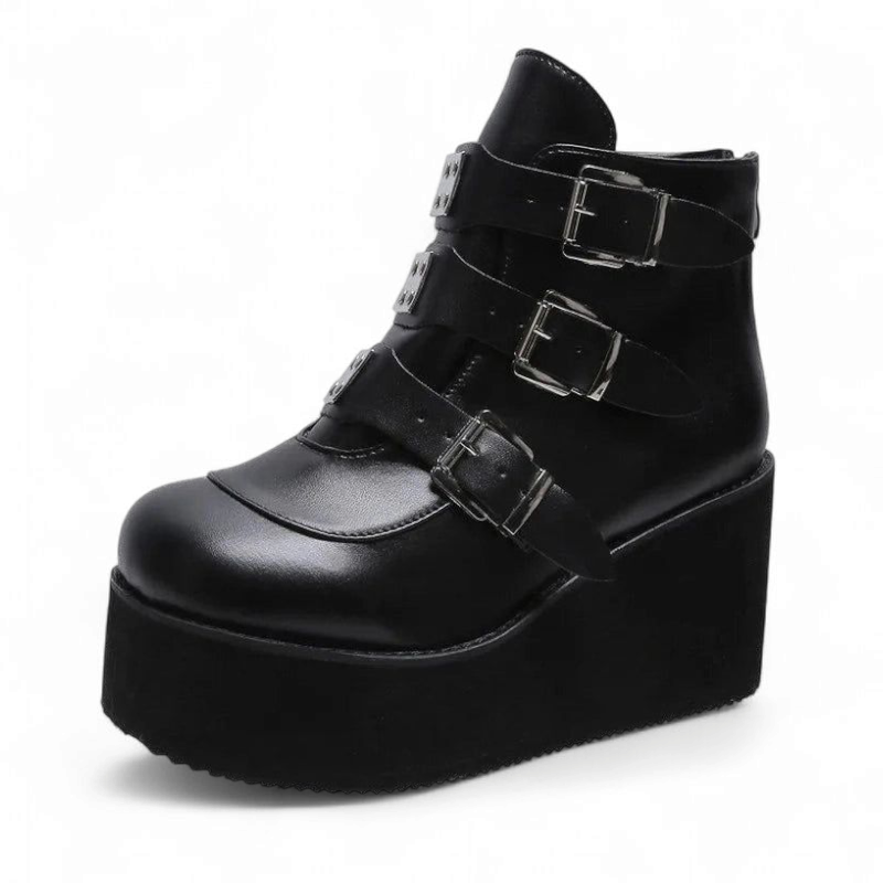 Side view of solid black wedge boot with metal buckles.