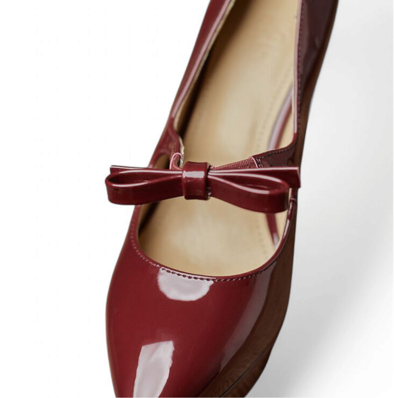 Close-up of glossy burgundy Mary-Jane shoe with slim bow and pointed toe.