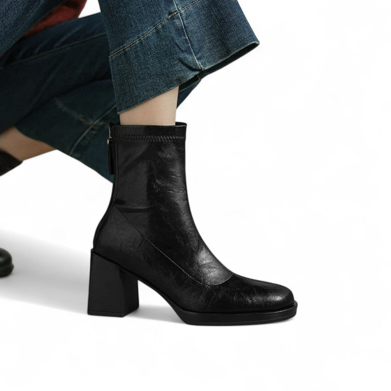 Detailed close-up of Black mid-calf boots with neat stitching and stable sole