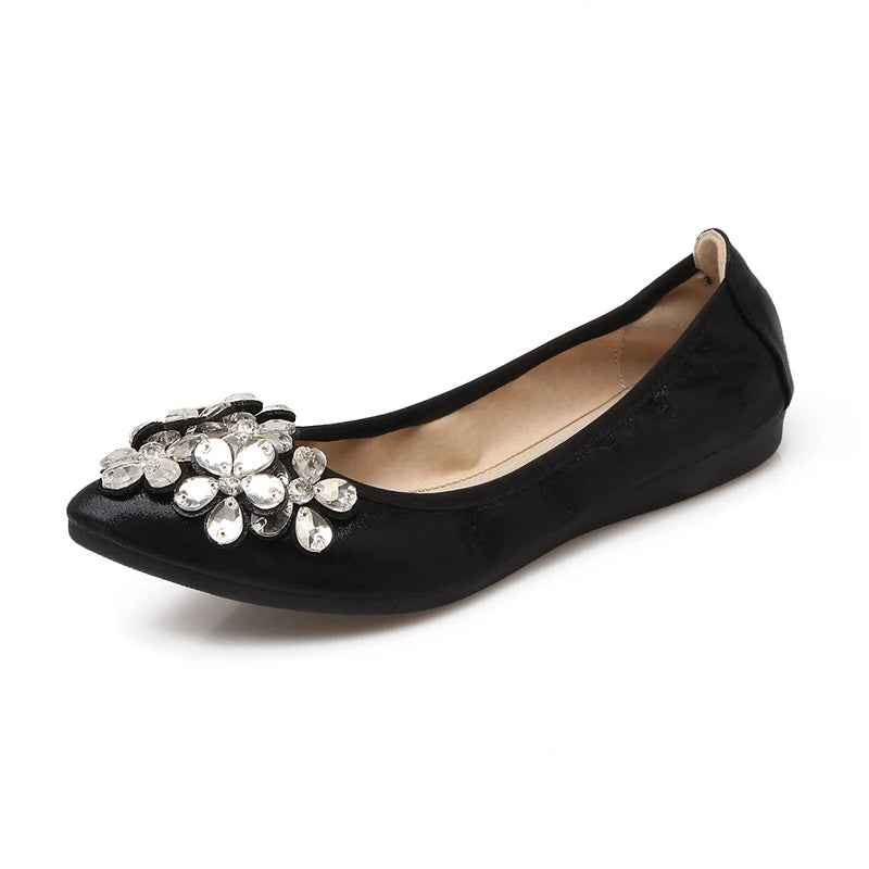 Black ballet flat featuring petal-like clear crystals on the toe, shown from a side angle.