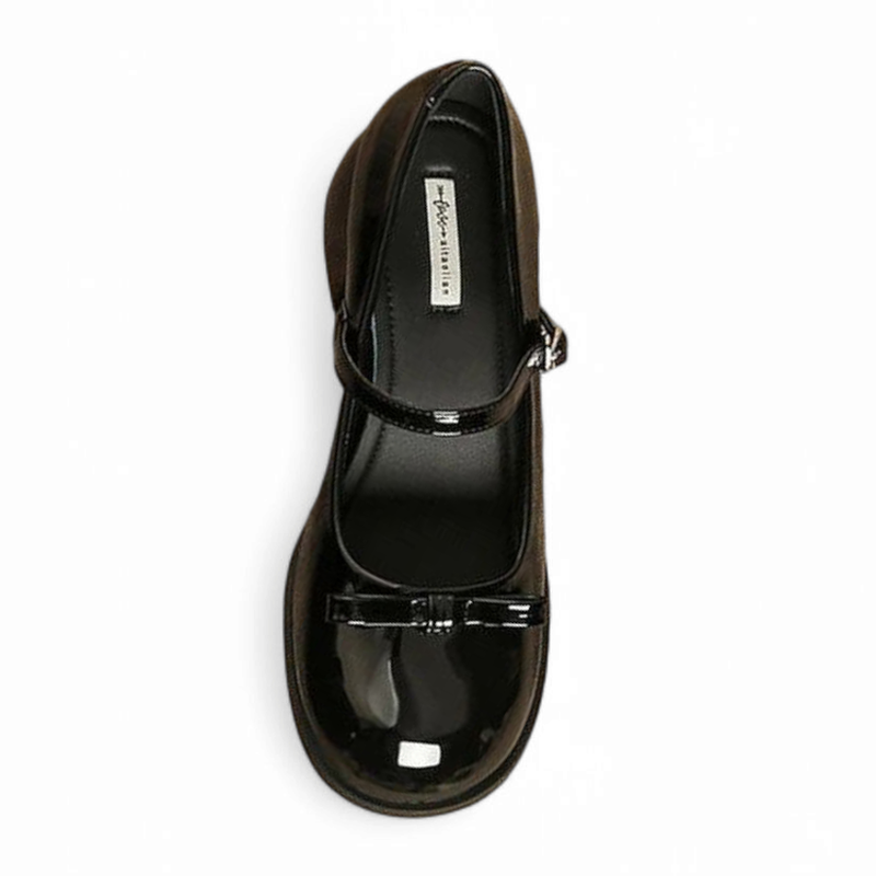 Top view of single glossy black Mary-Jane highlighting bow and slim strap.