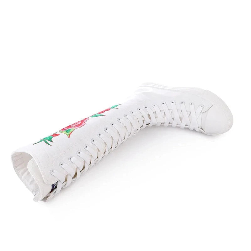 White canvas boot bent to demonstrate flexibility, full lacing visible.
