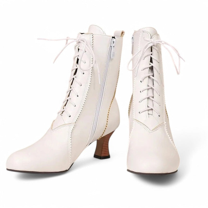 A pair of Merendy Samira white Victorian boots displayed on a plain background. One boot shows the front with a lace-up design, while the other reveals the side view with zipper and square heel. Round toe shape, scalloped trim, and subtle stitching are clearly visible.