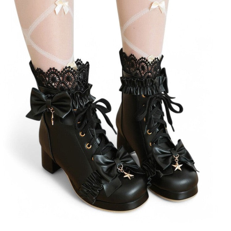 A woman wearing a black Victorian-style ankle boot, shown from the front. The image highlights the rounded toe, lace-up front, layered bows, and ruffled detailing, styled with feminine clothing.