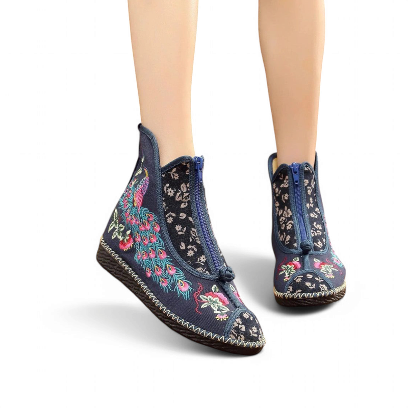 Navy embroidered peacock boot with blue front zip, side view on foot.