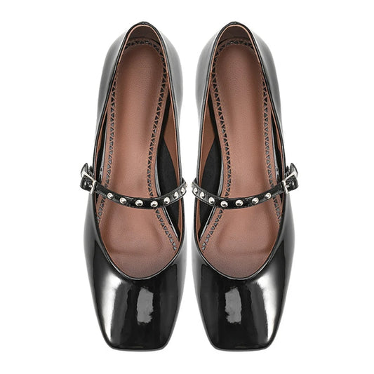 Overhead shot of black patent flat Mary Jane pair showing soft square toe and studded strap.