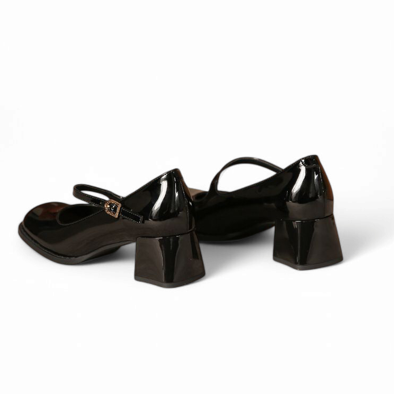 Pair of glossy black Mary-Jane pumps, rear angled view showing heels on white background.
