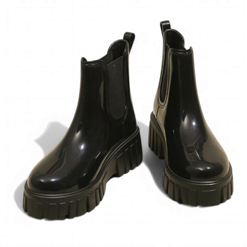 Glossy black Chelsea boots pair with subtle lighting on the surface