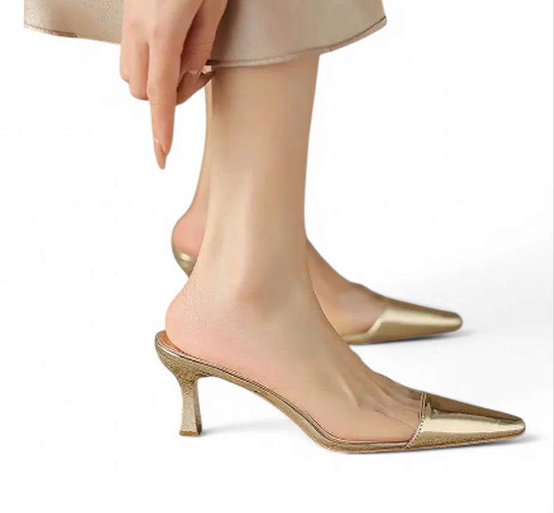 Gold backless mule with pointed toe and clear PVC vamp shown while walking.