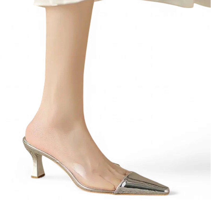 Silver metallic pointed mule with clear PVC vamp on foot with light dress.