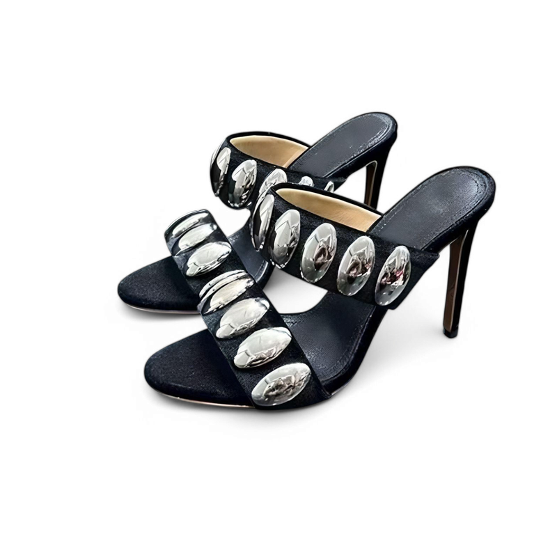 Close-up of slip-on mules with double black straps set with silver ovals.