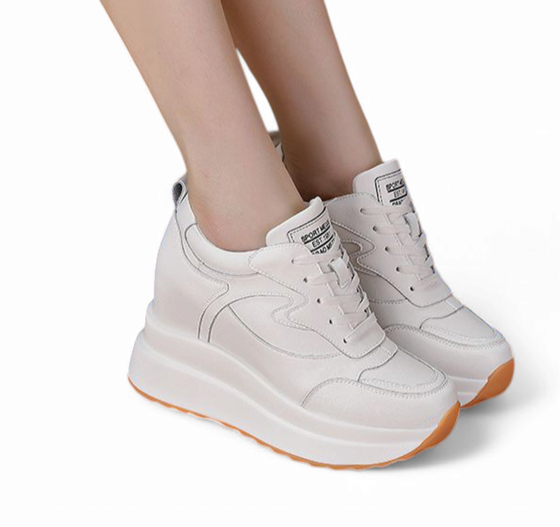 White wedge sneaker with round toe and laces, worn on two feet.