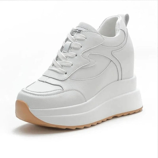 Front-angled white wedge sneaker highlighting the rubber sole shape.

